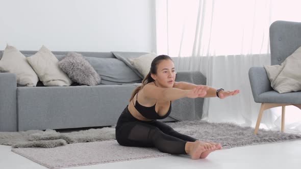 Sporty Young Woman Is Doing Stretching Exercises Sitting at Home Leans To Legs.