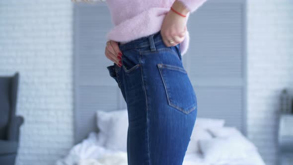 Adult Woman Trying To Zip Up Tight Jeans at Home alt
