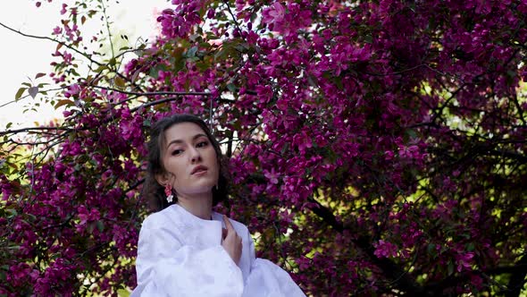 Fashion Portrait of a Young Beautiful Woman in a White Dress Standing and Posing Next to a Red alt
