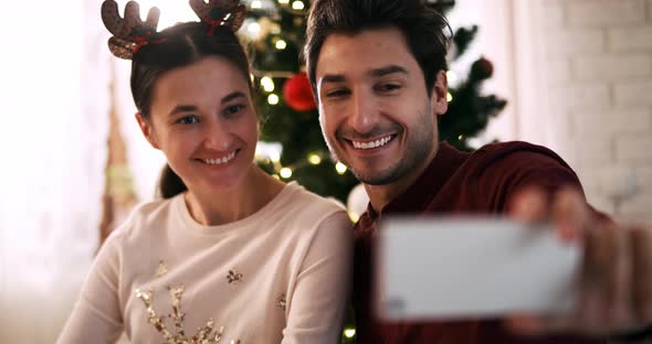 Handheld view of playful couple making a selfie at Christmas alt