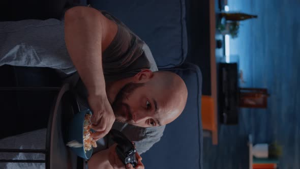 Vertical Video Competitive Determined Man Playing Videogame in Living Room at Night alt