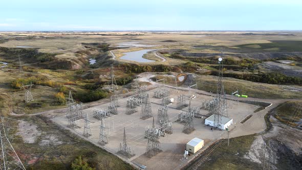 4k backwards flight over electricity masts and power lines in vast prairie setting. Warm colours dur alt