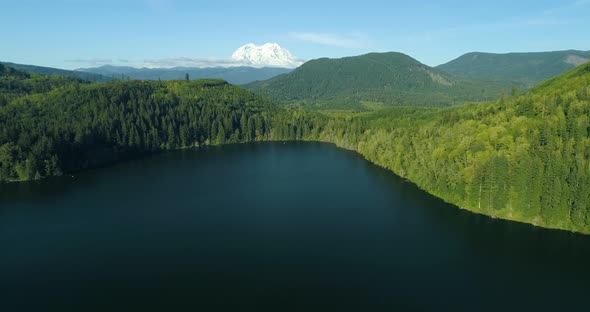 Large Snowy Mountain Peak Above Green Tree Hills Lake Aerial alt