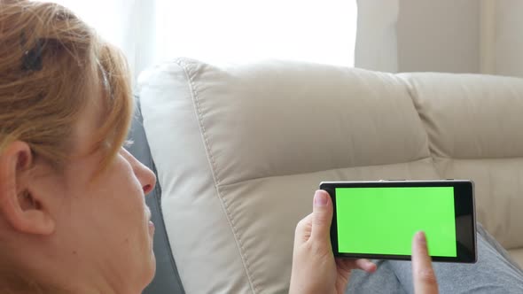 Modern green screen touch screen mobile phone in woman hands and scrolling pages 4K 2160p 30fps Ultr alt