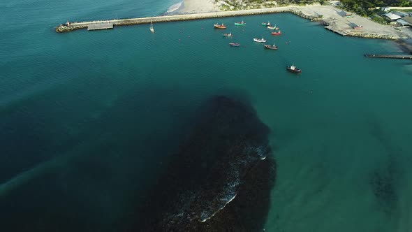 Aerial - Fly-over done over local fishing vessels anchored in small harbour of quaint fishing villag alt