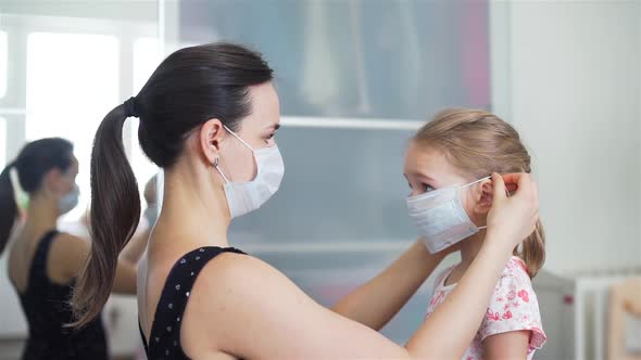 Woman Putting on a Medical Mask on Her Daughter alt