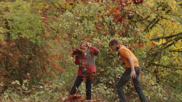 Two boys in Fall throwing leaves in slow motion