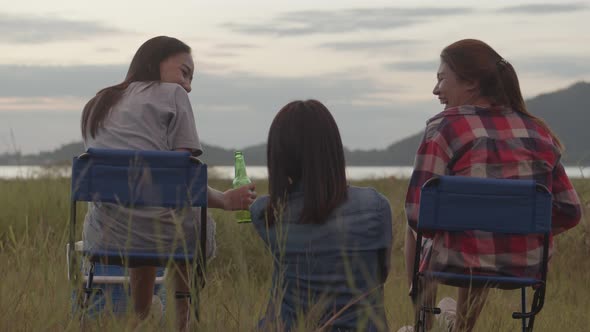 Group of a young teen Asian woman sitting on a chair with friends camping in nature.