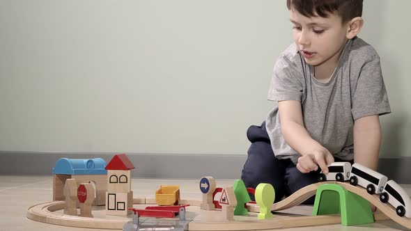 Cute boy plays with a wooden train, takes him across the bridge on flights. Wooden educational toys. alt