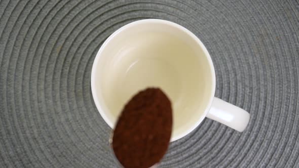 Ground Black Coffee Pouring From a Spoon Into a Cup