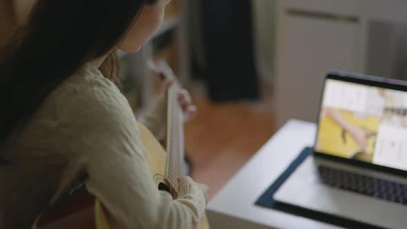 Young Asian Woman Playing Guitar at Home. Stay Home, Solo Activity Pretty Girl Watching Online alt