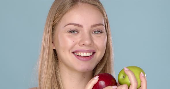 Close Up Studio Shot of Smiling Young Woman Holding Two Apples, Red and Green alt