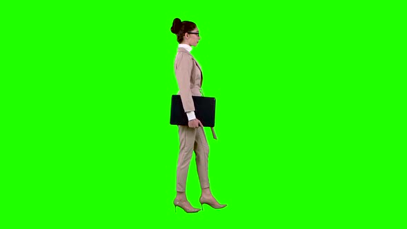 Girl Is Going To a Meeting with a Laptop in Her Hands. Green Screen. Side View. Slow Motion alt