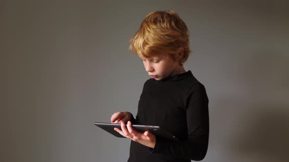 Portrait of young boy while surfing the internet on tablet