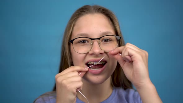 Girl with Braces Brushing Your Teeth with Dental Floss. A Girl with Colored Braces on Her Teeth alt
