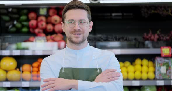 Close Up Portrait of Happy Man Worker in Glasses Wearing Apron Standing in Supermarket and Looking alt