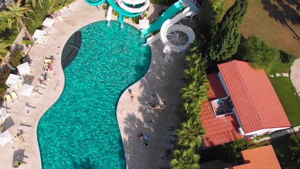 Fly Over a Large Pool with Blue Water and a Lot of Tourists in Hot Weather alt
