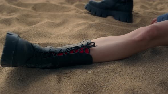Slim Legs Attractive Girl Lying Yellow Seashore Sand in Black Boots Close Up alt