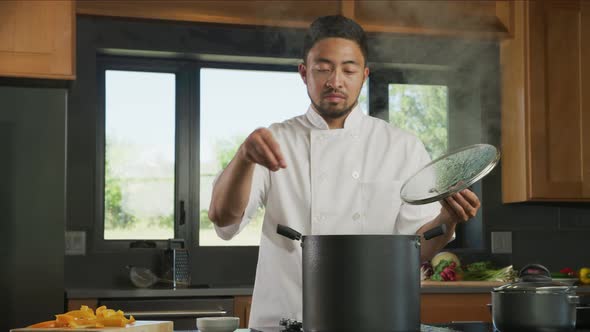 Chef drops seasoning into pot on stove