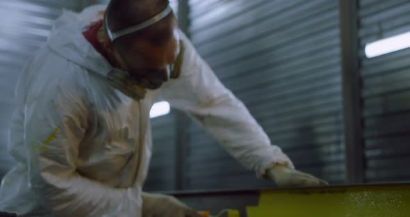 Man in Overalls and Protective Mask Paints Metal Structures with a Roller Yellow alt