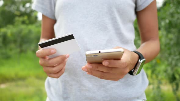 Beautiful woman shopping online and pay with a credit card number into a smartphone alt