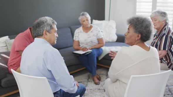 Mixed race senior female counsellor with clipboard advising to group of diverse senior friends alt