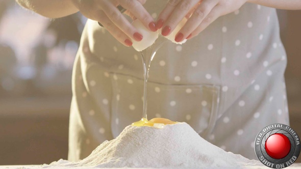 Woman Cracking Egg Into Flour In The Kitchen With Sun Shining In Slow Motion Shot On Red Camera alt