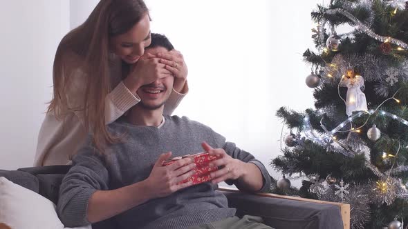 Woman Giving Surprise Christmas Gift for Man.