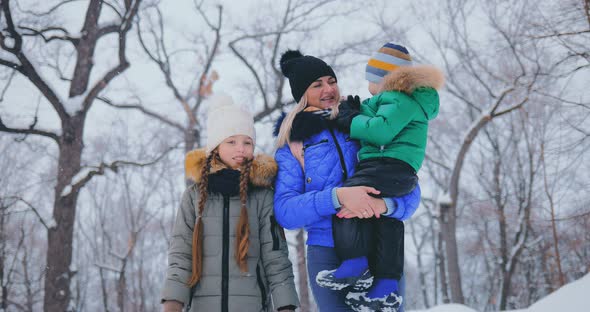 Happy Children Walk with Their Mother in the Winter in the Forest
