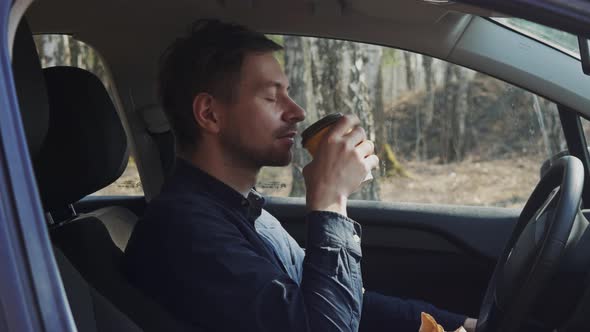 Young Guy Sitting in His Car Drinking His Morning Coffee to Cheer Himself Up