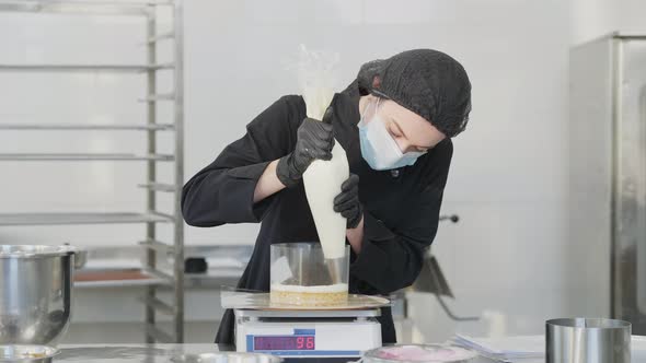 Portrait of Focused Female Confectioner Adding Layer on Baked Cake Dough Standing on Kitchen Scales alt