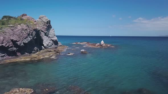 Camera Is Flying Over Turquoise and Clear Sea Water From Shore and Rocks, Aerial View