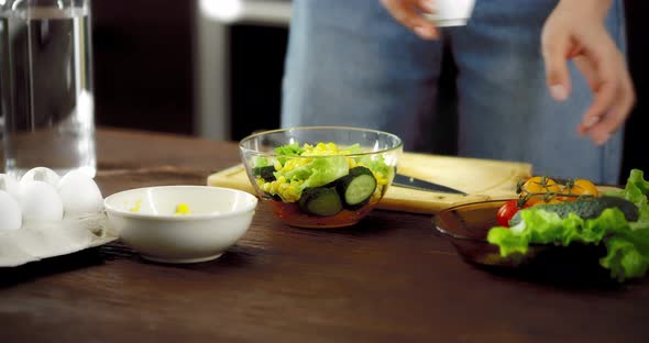 Women's Hands Pour Olive Oil Into a Fresh Salad in a Bowl