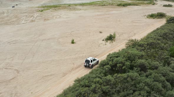 Aerial View of a Car Driving on Sand alt