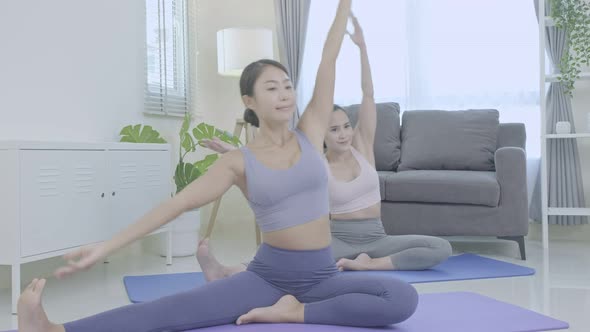 Asian people practicing yoga lifestyle class on a mat at living room