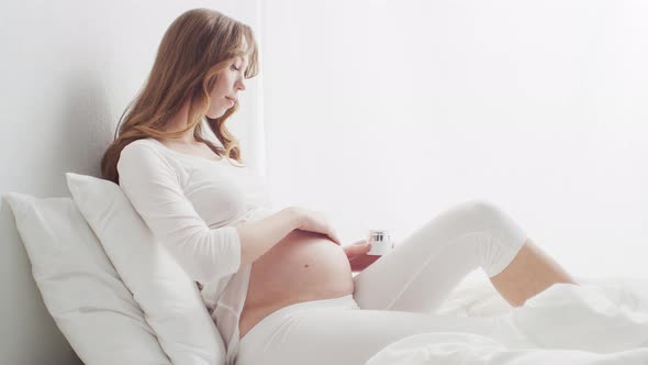 Pregnant woman touching her belly. Pregnancy, motherhood, and expectation concept. alt