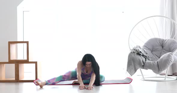 Young attractive woman wearing sportswear, pants and top, doing stretching yoga exercises.