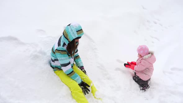 Mom with a Three-year-old Daughter Play Snowballs alt