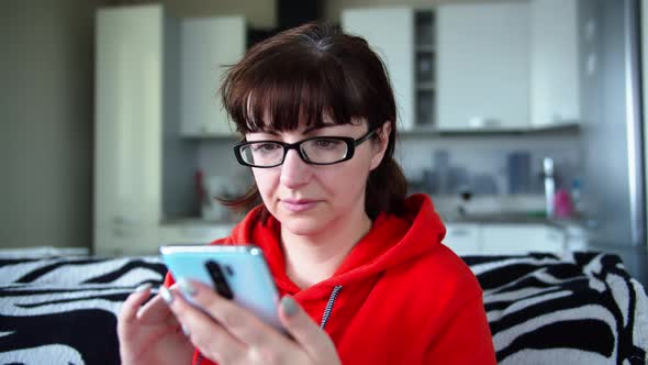 Woman with Glasses at Home Uses Phone, Chat with Friends, Read Some Information