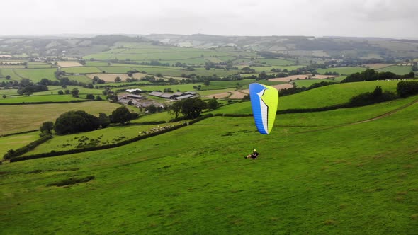 Aerial shot of a Paraglider flying over a field and Countryside in East Devon England alt