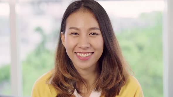 Asian woman feeling happy smiling and looking to camera while relax in her living room. alt