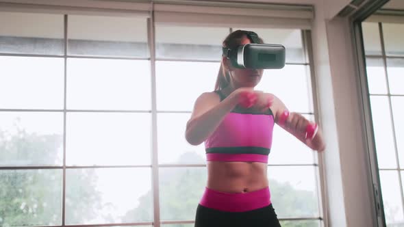 Young Asian woman wearing virtual reality glasses while working out at home. alt