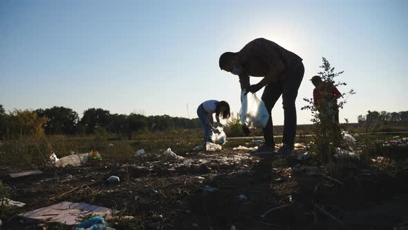 Family of Eco Activists in Masks Cleaning Meadow of Plastic and Paper Waste alt