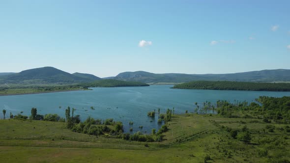 Aerial View on Water Reservoir at Mountain Valley Covered with Green Spring Forest alt