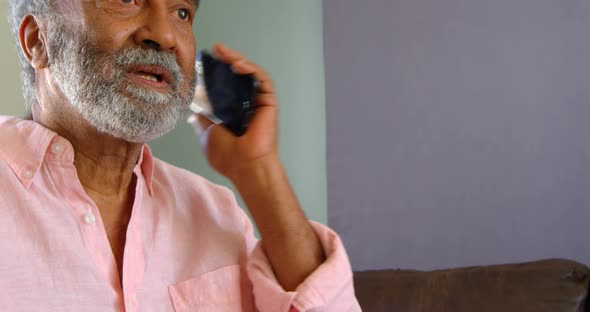 Side view of old asian senior man talking on mobile phone at home 4k alt