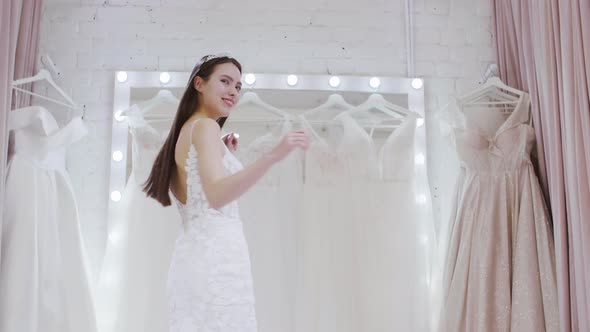 Smiling Brunette Trying on Wedding Dress in Store alt