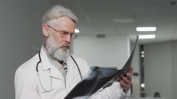 Elderly Male Doctor Examining Xray Scans of a Patient