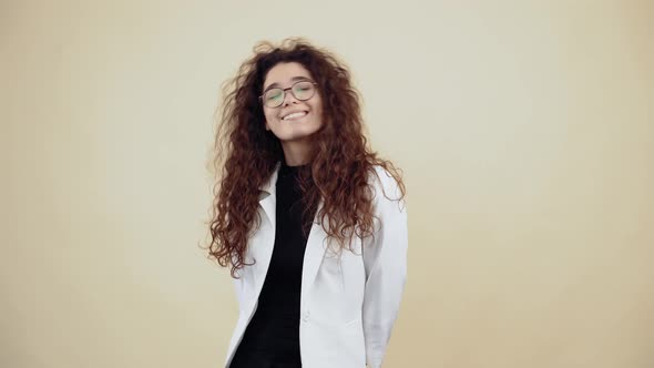 Shy Young Woman with Curly Hair Smiles with Her Teeth and Looks Into the Room alt