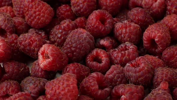 4K Beautiful ripe raspberry rotates on a plate. Slow rotation of raspberries close-up top view.