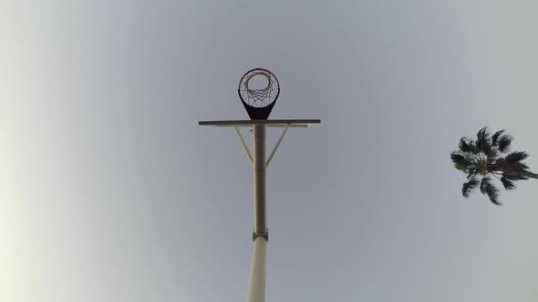 Low angle worms eye view of a young man playing basketball on the beach. alt